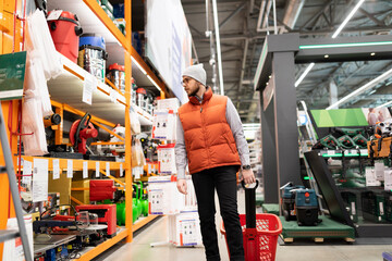 a man in a hardware store does not choose an air compressor and gas generator