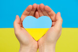 Fototapeta Tęcza - Yellow-blue heart in the color of the flag of Ukraine in the hands of a person, a place for text. Love for one's country, Constitution Day and Independence Day