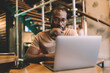 © BullRun - Millennial copywriter in classic eyewear checking received email messages on digital laptop computer using coworking internet for doing distance job, African American programmer in spectacles chatting