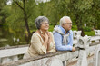 © Studio Romantic - Happy cheerful relaxed old senior couple standing on bridge enjoy good weather and green natural park landscape. Retired romantic caucasian couple. Healthy weekend on retirement concept