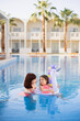 © sofiko14 - Family look, swimwear outfit. Beautiful mother with her pretty daughter with an inflatable ring in the form of a unicorn having fun and relaxed on swimming pool on villa beach. Summer time vacations