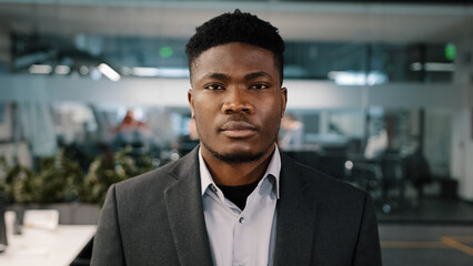 Close up portrait African american young businessman entrepreneur investor confident male face concentrated expression looking at camera seriously man thinking decision in office workspace background