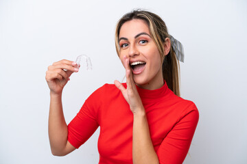 Wall Mural - Young caucasian woman holding invisible braces on white background whispering something