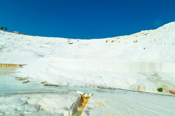 Wall Mural - Natural travertine pools and terraces in Pamukkale. Cotton castle in southwestern Turkey. Tourists walking and bathing in Natural travertine pools