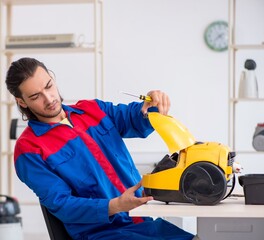 Wall Mural - Young male contractor repairing vacuum cleaner at workshop