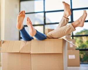 Poster - Handle with care. Shot of an unidentifiable young couple lying in a box together with their feet sticking out.