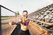 © padnob - Smiling young active sport woman stretching and turning her face to the sunset beside of the running track