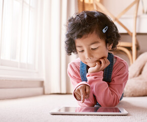 Wall Mural - Which one should I watch. Shot of a little girl using a digital tablet at home.