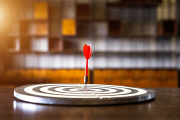 Wall Mural - Red dart arrow hitting in the target center of dartboard on bullseye with sun light vintage style, Target marketing and business success concept