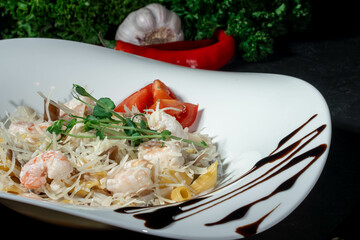 Wall Mural - Italian pasta with shrimp and cheese. Italian pasta fettuccine on a white plate on dark background