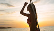 Portrait of sexy Asian woman in colorful bikini and sunglasses standing, looking away and enjoying sunset on her private yacht. Freedom, vacation, summertime fun concept