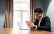 © muse studio - A male manager works in an office coworking space, uses a laptop and writes a letter to a client