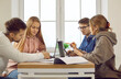 © Studio Romantic - Diverse students sit at desk brainstorm study together preparing for exam. Young people or friends at table work on laptop doing research for university or college project. Education concept.