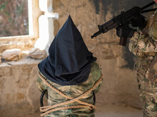 A Caucasian Woman In An Army Uniform Holds A Hostage With A Bag On Her Head At The Sight Of A Machine Gun. 
