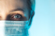 © PoppyPix - Close up portrait photo. Eye of young female doctor. Protection against contagious disease through wearing hygienic face surgical medical mask. High quality photo