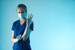 © PoppyPix - Young caucasian woman doctor putting on a white sterile glove, preparing herself for surgery. Medium studio shot, blue background. High quality photo