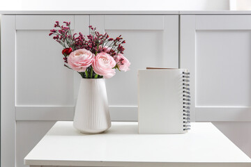 Wall Mural - Bouquet of pink Persian buttercups on a white table in front of a chest of drawers. Scandinavian style. Place for text