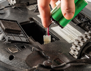 the serviceman changes the faulty battery in the robot vacuum cleaner.