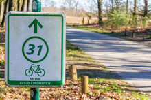 Bicycle Route 31 Sign, Inscription: Region Eindhoven, A Cycle Path With Bare Trees In The Blurred Background, Sunny Day In The Dutch Nature Reserve Natuurpoort Vennenhorst, North Brabant, Netherlands