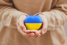 The Concept Of Ending The War In Ukraine. Women's Hands Holding The Ukraine Flag Painted Heart. Family, Patriotism, Unity, Support.