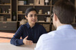 © fizkes - Confident Indian female meet male business partner investor sit at negotiation table talk discuss commercial deal explain project benefits. Smart young lady tell about herself to hr on job interview