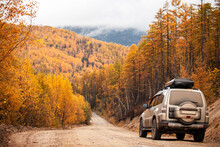 SUV On Scenic Autumn Road In The Forest