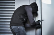 © Chanelle M/peopleimages.com - Hes almost found a way to get inside. Rearview shot of a male burglar busy picking the lock of a door in a garage.