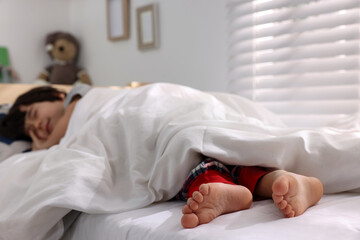 Wall Mural - Little boy sleeping in bed at home, focus on feet