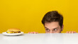 Hungry Guy Looking At Burger Peeping Out Table