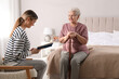 © New Africa - Young caregiver reading book to senior woman in bedroom. Home care service