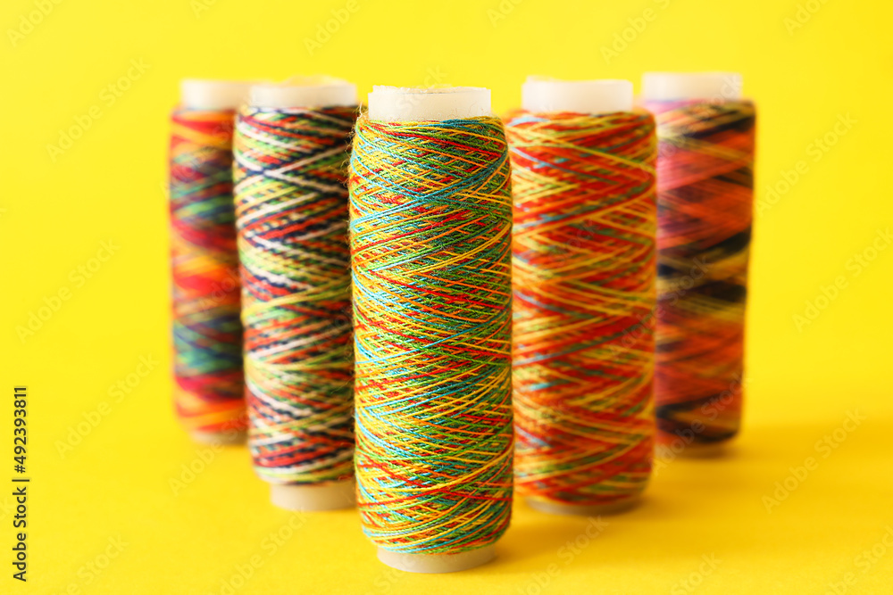 Rainbow sewing thread spools on color background
