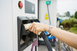 © DG PhotoStock - Unrecognizable Asian woman holding a DC - CCS type 2 EV charging connector at EV charging station.