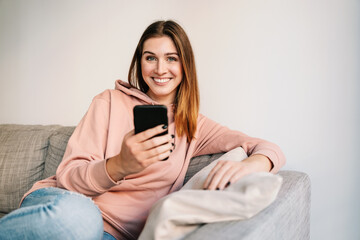 happy woman using mobile phone on sofa