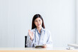 © Anatta_Tan - Portrait images of Asian attractive doctor woman, sitting on a table at workplace, are smile and happily On white background, to people and health concept.