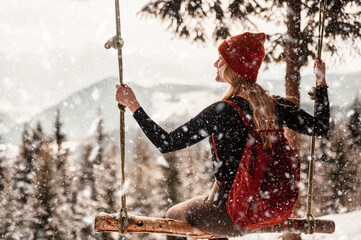 Woman swinging on swing in sunny winter dayin the ferest. Wooden swing with swinging free, happy woman outdoors. Healthy lifestyle vacation