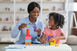 © Prostock-studio - Friendly teacher exercising with happy little girl at kindergarten