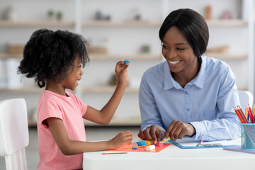 Wall Mural - Cute little black girl and teacher playing with play dough