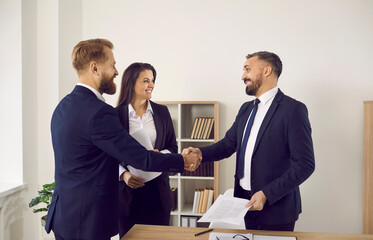 Wall Mural - Smiling businesspeople shake hands close deal or make agreement at meeting in office. Happy diverse business partners handshake get acquainted greeting at negotiations. Partnership concept.