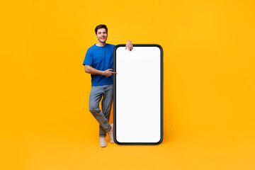 Wall Mural - Guy pointing and leaning on big white empty smartphone screen