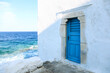 Traditional white building with blue door at the seaside. Mykonos island, Greece