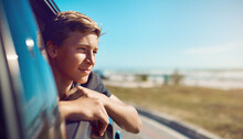 Now Thats A View. Shot Of A Happy Young Boy Leaning Out Of The Car Window On A Trip To The Beach.