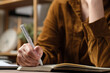 © weedezign - close uop woman hand writing on notebook at worknig desk at home