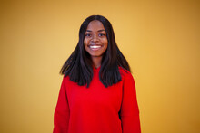Beautiful Smiling African-american Girl In A Red Hoodie Looking At The Camera On A Yellow Background With Copy Space