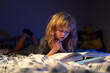 © Volodymyr - Child reading a book in bed before going to sleep. Child reading a book on bedtime night. Boy reading bedtime story, fairy tale. Kids reading books.