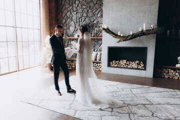 Wall Mural - The first meeting of the groom in a black suit and the bride in a white wedding dress with a bouquet in the interior of a photo studio, hotel, on black background