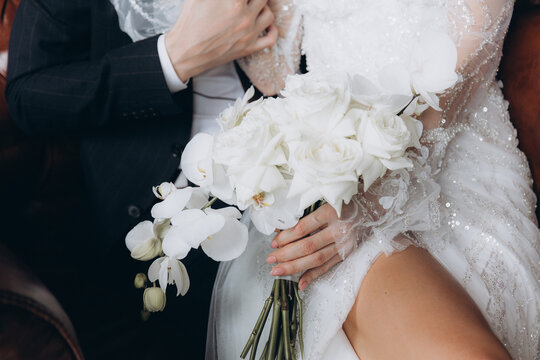 The first meeting of the groom in a black suit and the bride in a white wedding dress with a bouquet in the interior of a photo studio, hotel, on black background