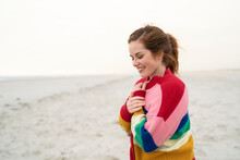 Happy Young Woman Wearing Multi Colored Sweater Standing On Beach