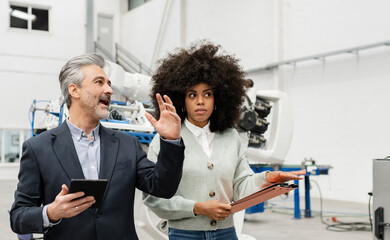 Businessman holding tablet PC discussing with developer in factory