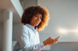 © Westend61 - Smiling working woman with smart phone at working place