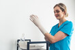 © PoppyPix - Young nurse in a blue uniform putting a latex glove on her hand. High quality photo